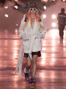 Front full-body runway view of white chunky knit cardigan with fringe and oval sunglasses