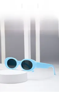 Close-up detail of light blue oval sunglasses with thick frames and grey UV lenses