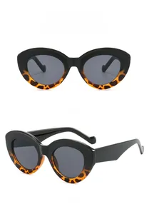 Detail view of oval cat-eye sunglasses with black and leopard print frame and grey lenses
