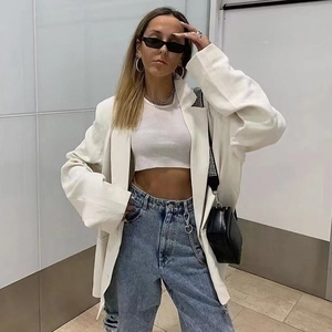 Photo street style d'une femme en blazer blanc oversize et lunettes de soleil carrées noires