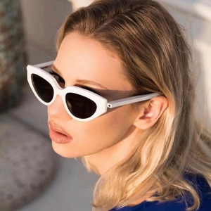 Close-up of white small frame cat eye sunglasses worn by a model in outdoor sunlight
