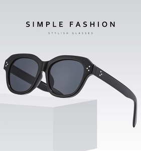 Close-up of matte black frame sunglasses with three-point silver rivets and grey lenses