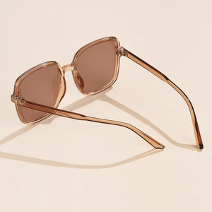 Detail of square oversized sunglasses with transparent amber frame and brown lenses