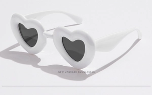 Détail de lunettes de soleil en forme de cœur avec monture épaisse blanche sur fond blanc