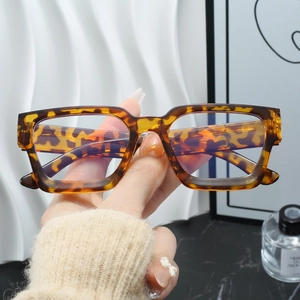 Detailaufnahme einer übergroßen Brille mit Schildpattmuster, gehalten vor Marmorhintergrund