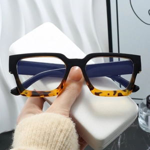 Nahaufnahme der quadratischen schwarz-schildpattfarbenen Brille über einem weißen Lederetui