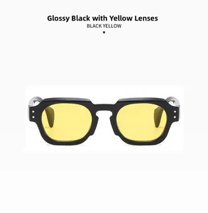 Close-up of retro thick black frames with yellow lenses and dual silver stud rivets