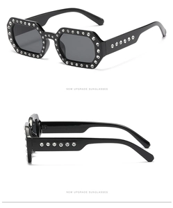 Close-up of rectangular black sunglasses with sparkling rhinestones on the frame and temples
