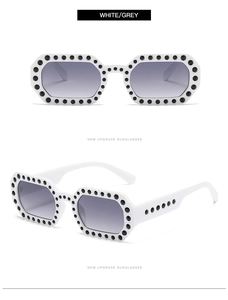 Detail of white sunglasses with black polka dots and grey gradient lenses in a macro view