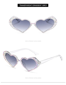 Detail view of heart-shaped sunglasses with transparent frame and colorful gradient rhinestones