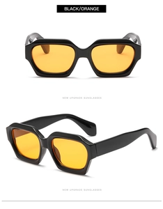 Detail view of bold black polygonal sunglasses with vibrant orange lenses and thick frames