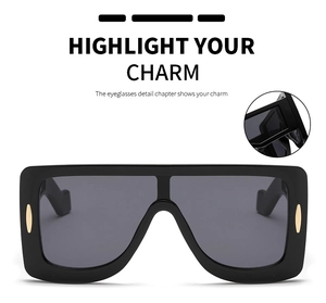 Detail of oversized square sunglasses with black wide frame and gold oval metal accent