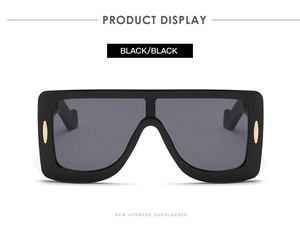 Detail of square oversized sunglasses with gold oval temple accents and dark lenses
