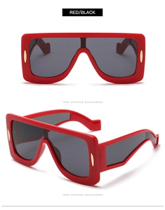Detailed view of oversized red square sunglasses with thick frames and metal rivets