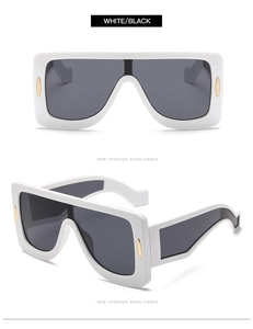 Detail of white oversized square sunglasses with gold metal accents and wide folded temples