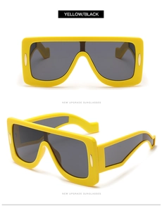 Detail of oversized yellow frame sunglasses with integrated black lenses and gold accents