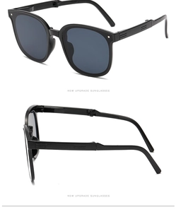 Detail view of foldable black sunglasses showing the hinge mechanism and grey lenses