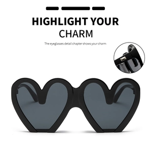 Detailaufnahme der herzförmigen Sonnenbrille mit schwarzem Rahmen und Goldnieten
