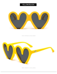 Detail einer gelben herzförmigen Sonnenbrille mit schwarzen Gläsern und Silberakzenten