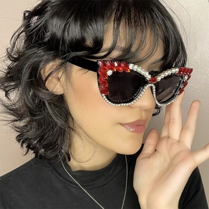 Close-up of cat-eye sunglasses with red marquise rhinestones and black frame on model
