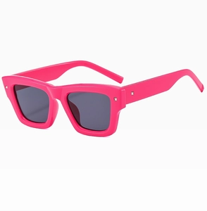 Close-up of bright pink square frame sunglasses with stylish metal rivets on corners
