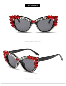 Detail of cat eye sunglasses with red rhinestones and dark lenses on white background