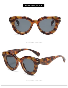 Detail of hawksbill textured sunglasses with golden wing accents and dark grey lenses