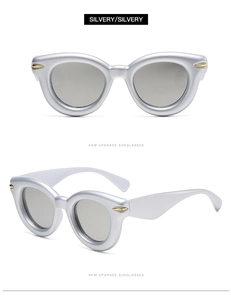 Detail of silver oval sunglasses with vintage thick frames and golden metal arrow accents