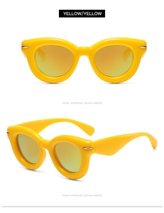 Detail shot of bright yellow thick frame cat-eye sunglasses with golden reflective lenses