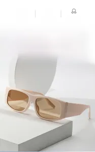 Detail of cream oval sunglasses featuring wide temples and tinted amber lenses
