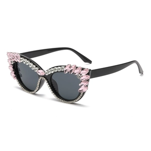 Cat eye sunglasses with pink crystal embellishments and rhinestone border in black frame