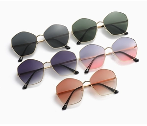Flat lay of stylish polygon sunglasses with metallic frames in various gradient lens colors