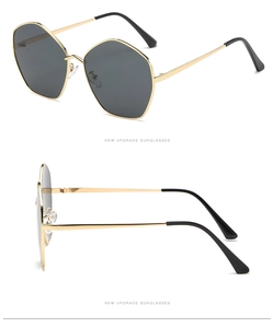 Detail view of gold polygon sunglasses frame with dark lenses and adjustable nose pads