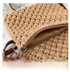 Detail shot of smooth zipper closure on hand-woven khaki beach bag with brown strap