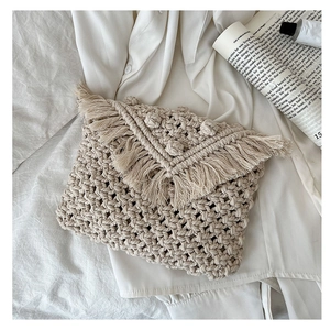 Close-up of bohemian macrame woven texture and elegant long fringe on cream cotton bag