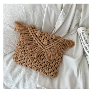 Macro detail of tan woven cotton crossbody bag featuring dense fringe on the fold-over flap