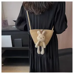 Détail du sac seau en paille avec un lapin en peluche mignon et fermoir en perle