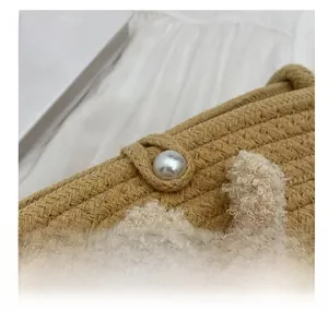 Détail d'un sac seau en paille tressé main avec fermoir perle et breloque en peluche blanche