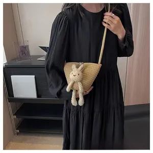 Détail du sac seau tressé en paille avec lapin en peluche et fermoir perle élégant