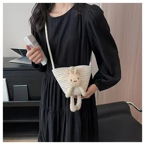 Détail d'un sac seau tissé avec une poupée lapin en peluche et fermoir perle unique