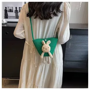 Détail du sac seau tissé vert avec un lapin en peluche et un fermoir en perle