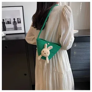 Détail du sac tissé main vert avec un lapin en peluche 3D et un bouton en perle