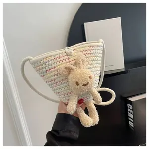Détail d'un sac seau en paille avec broderie ondulée colorée et charmant lapin en peluche