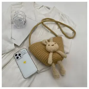 Détail d'un sac seau tressé avec un charm lapin en peluche sur fond blanc minimaliste