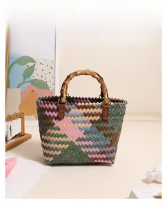 Detail of multi-color woven straw bag featuring rustic bamboo handles and geometric pattern