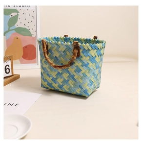Detail of blue and green woven handbag with bamboo-style handle in a home setting