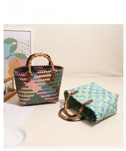 Detail of colorful woven straw bag featuring a natural bamboo handle and mixed color pattern