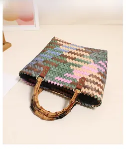 Detail of multi-color woven straw beach bag featuring bamboo handle and leather straps