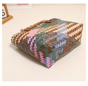 Detail of colorful woven tote bag featuring bamboo-style handles and a reinforced wide base