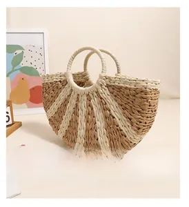 Detail view of semi-circular woven straw bag with natural bicolor textures and round handles